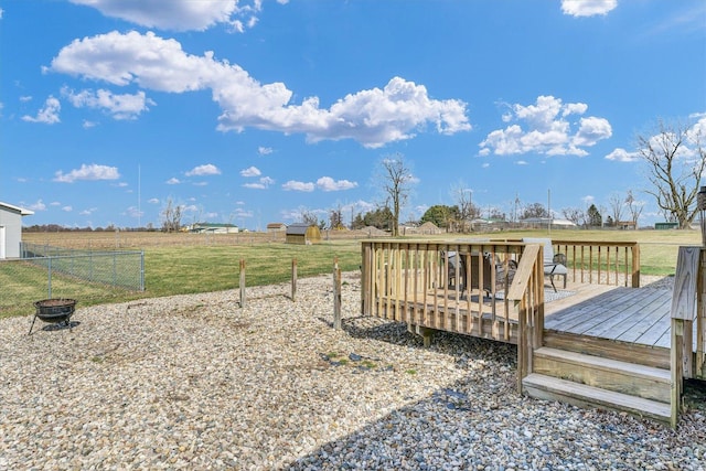 view of yard featuring an outdoor fire pit, a rural view, fence, and a deck