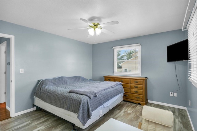 bedroom featuring baseboards, wood finished floors, and ceiling fan