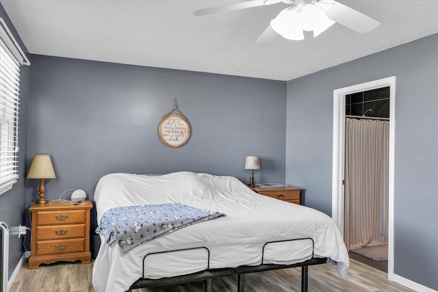 bedroom with multiple windows, wood finished floors, ceiling fan, and baseboards