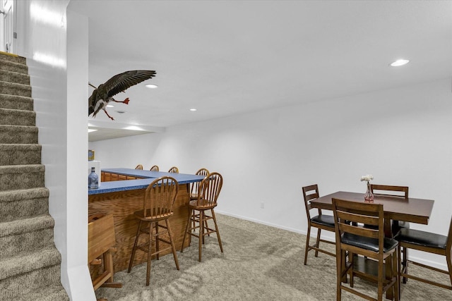 carpeted dining area featuring baseboards, stairs, recessed lighting, and bar area