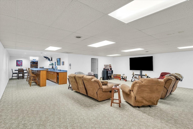 living room with indoor bar, light colored carpet, and a paneled ceiling