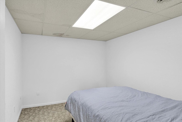carpeted bedroom with baseboards and a paneled ceiling
