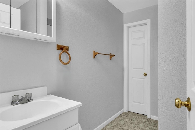 bathroom featuring baseboards, a textured wall, and vanity