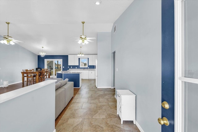 living area with baseboards, visible vents, vaulted ceiling, and ceiling fan with notable chandelier