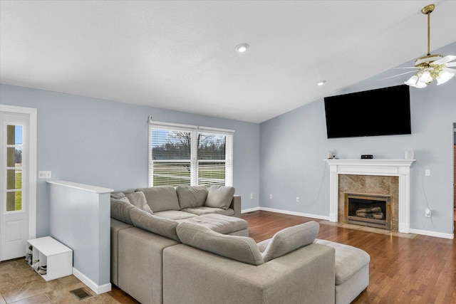 living room featuring lofted ceiling, baseboards, ceiling fan, visible vents, and wood finished floors