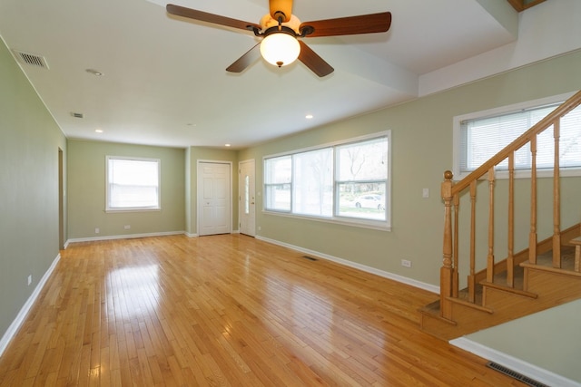 unfurnished living room featuring stairs, light wood-style flooring, baseboards, and visible vents