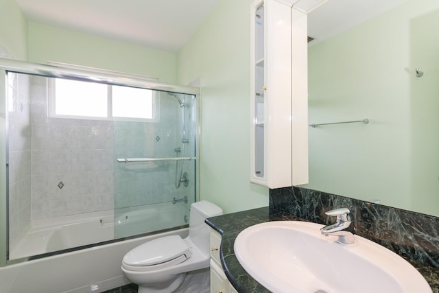 bathroom with vanity, toilet, and combined bath / shower with glass door