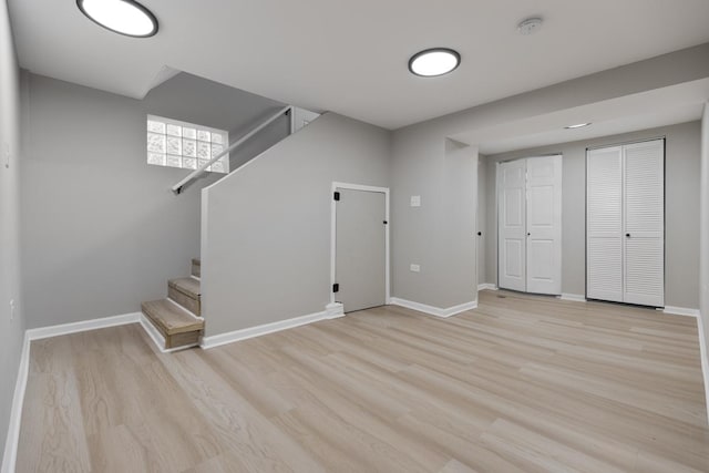 basement with stairway, light wood-style floors, and baseboards