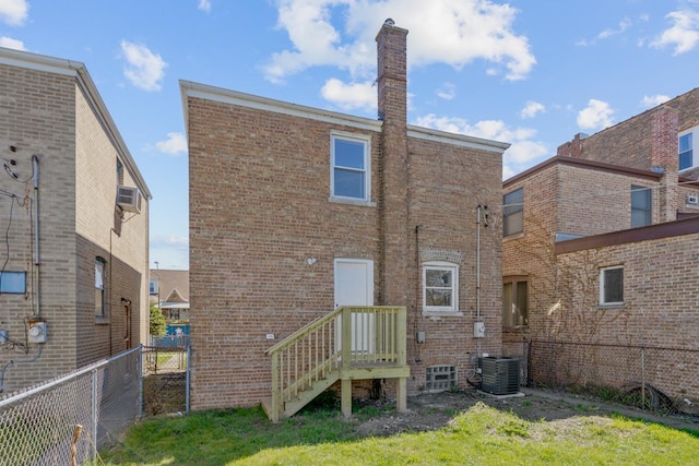 rear view of house with central air condition unit, brick siding, a chimney, and fence