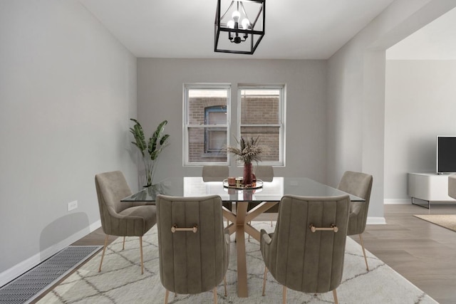 dining space with baseboards, an inviting chandelier, and wood finished floors