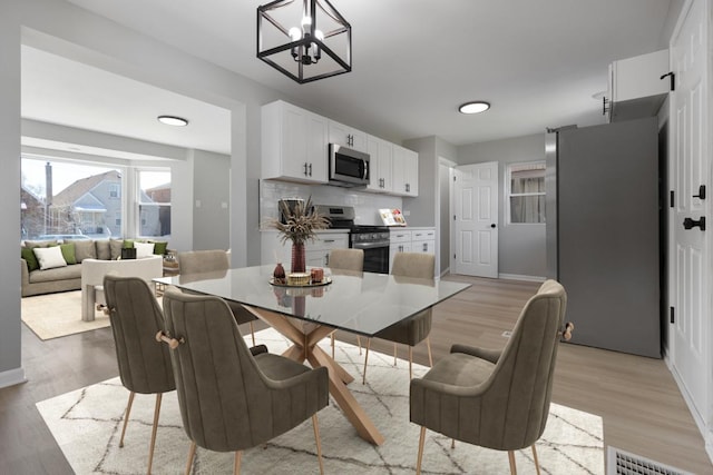 dining room with visible vents, baseboards, light wood-style flooring, and a chandelier