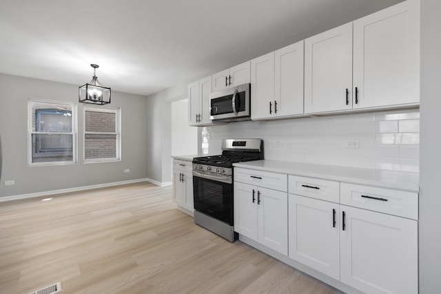 kitchen with tasteful backsplash, light countertops, light wood-type flooring, appliances with stainless steel finishes, and white cabinets