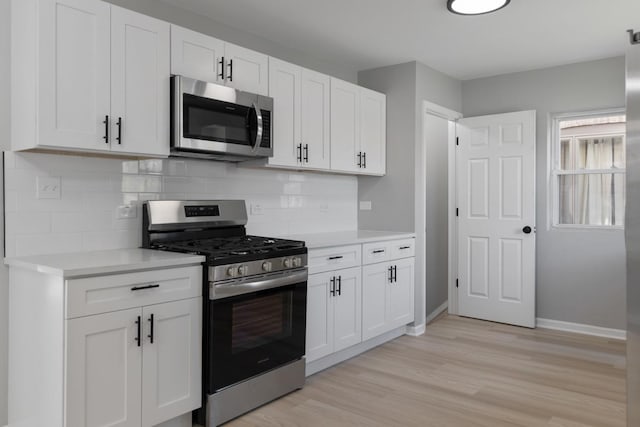 kitchen with light wood-type flooring, backsplash, white cabinetry, stainless steel appliances, and light countertops