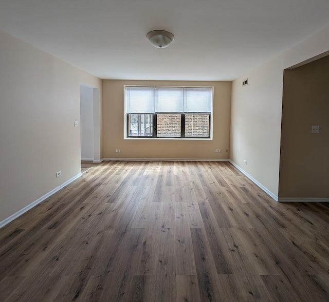 empty room featuring visible vents, baseboards, and wood finished floors