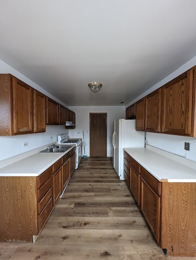 kitchen featuring a sink, white appliances, light countertops, and light wood finished floors