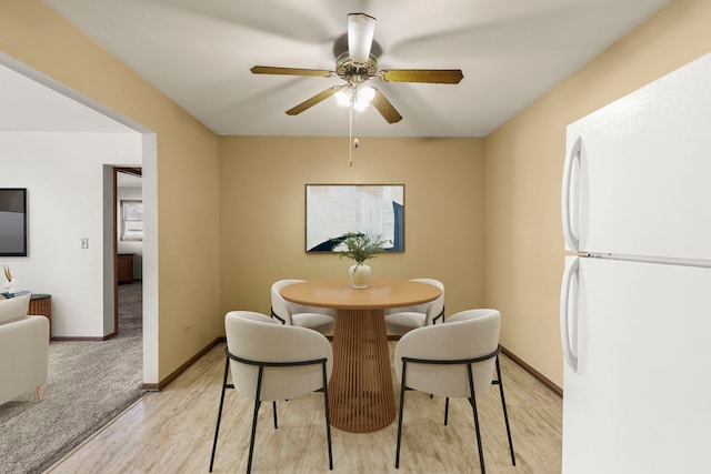 dining area featuring light wood-type flooring, baseboards, and ceiling fan