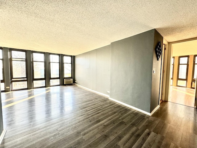 unfurnished living room with a textured ceiling, wood finished floors, baseboards, and a wall mounted AC