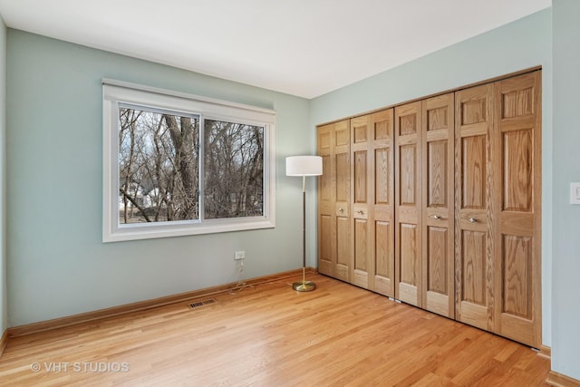 unfurnished bedroom with visible vents, a closet, and wood finished floors