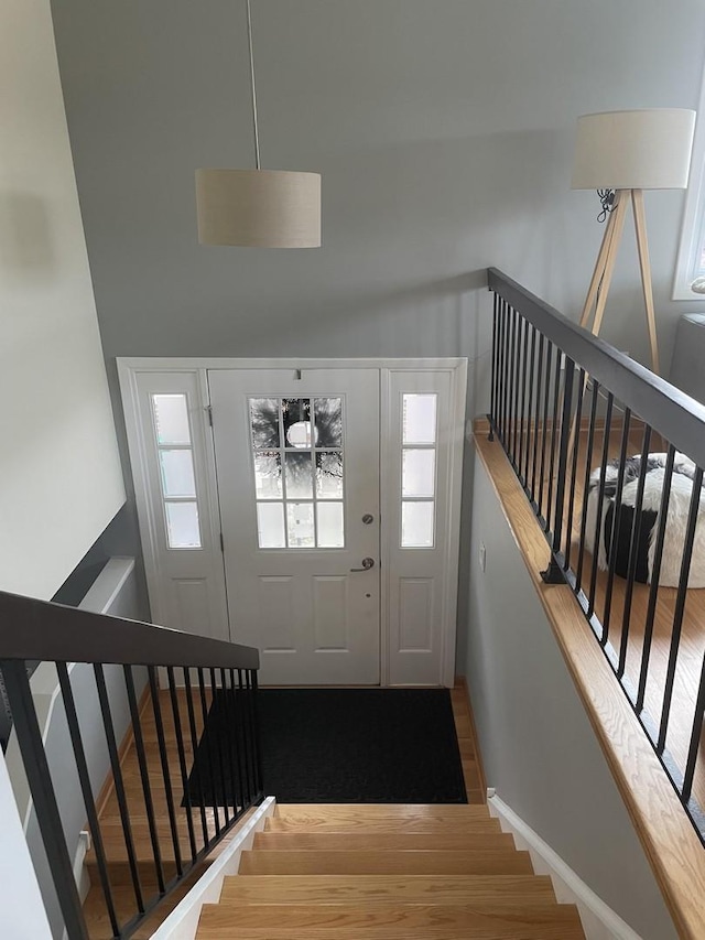 foyer featuring baseboards, stairs, a towering ceiling, and wood finished floors