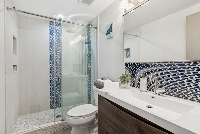 full bathroom with vanity, visible vents, a shower stall, toilet, and tasteful backsplash