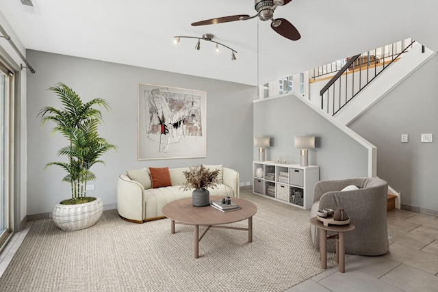 living room with stairway, light tile patterned floors, a ceiling fan, visible vents, and baseboards