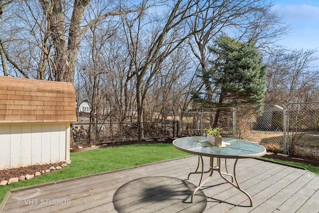 wooden terrace featuring an outdoor structure, a yard, and fence