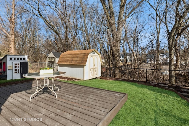 wooden deck with an outdoor structure, a storage unit, a lawn, and a fenced backyard