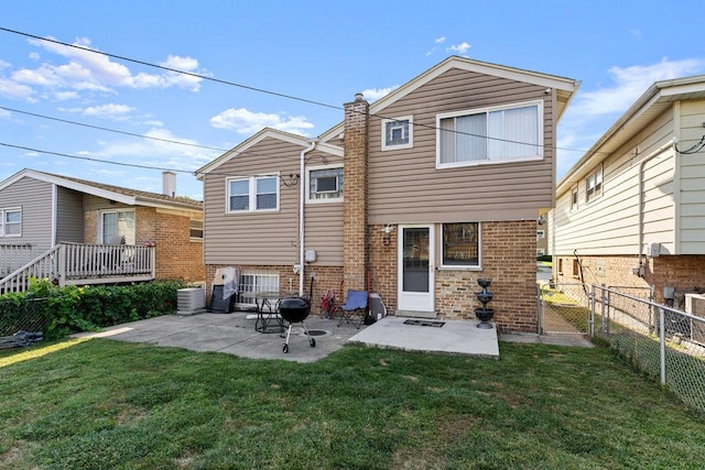 rear view of house featuring fence, a lawn, brick siding, and a patio area