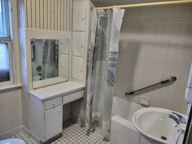 bathroom with a sink, shower / tub combo with curtain, and tile walls