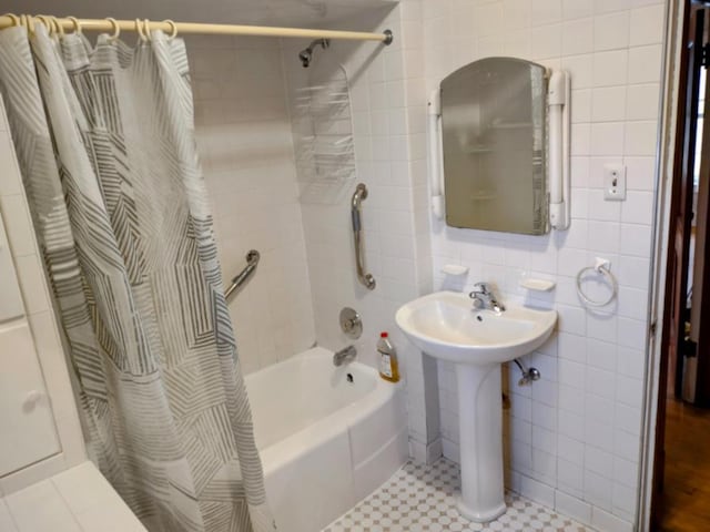 bathroom with a sink, tile walls, and shower / bathtub combination with curtain