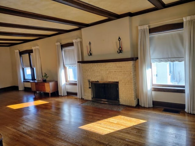 unfurnished living room with beam ceiling, wood finished floors, visible vents, and baseboards