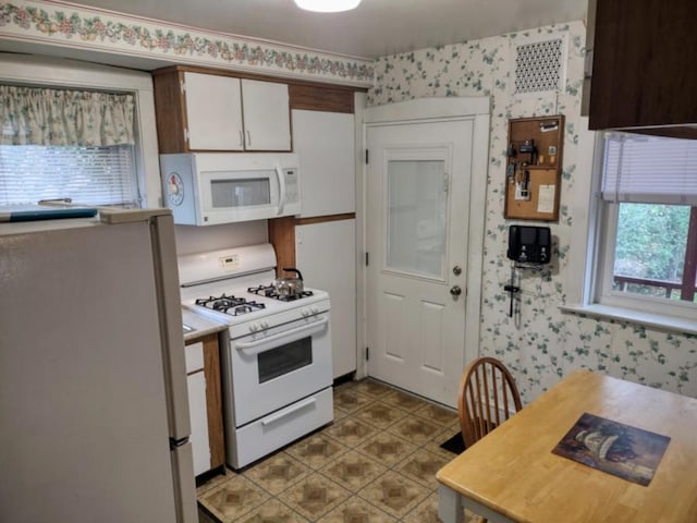 kitchen featuring white appliances, white cabinets, light countertops, and wallpapered walls