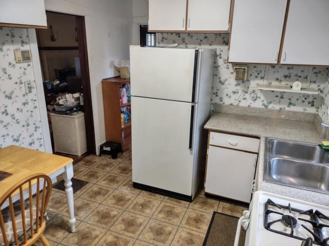 kitchen featuring light countertops, light tile patterned flooring, white cabinets, white appliances, and a sink