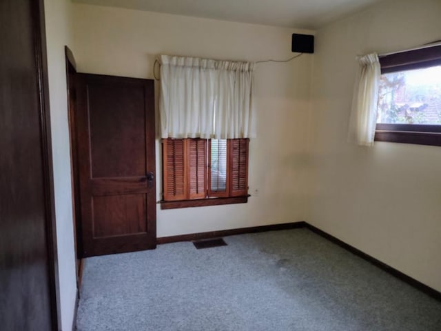 carpeted empty room featuring visible vents and baseboards