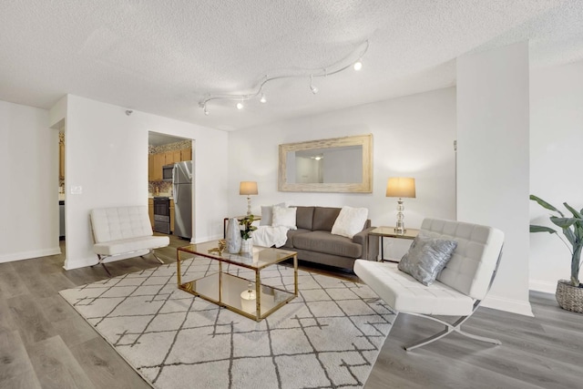 living room featuring a textured ceiling, baseboards, and wood finished floors