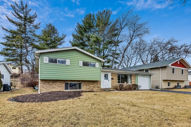 tri-level home featuring a front lawn, brick siding, a garage, and driveway