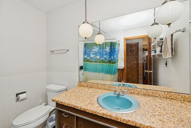 bathroom featuring curtained shower, toilet, vanity, wainscoting, and tile walls