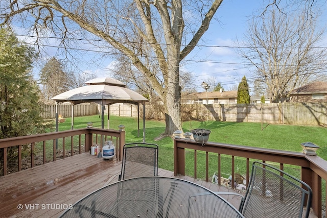 wooden deck with outdoor dining space, a gazebo, a lawn, and a fenced backyard