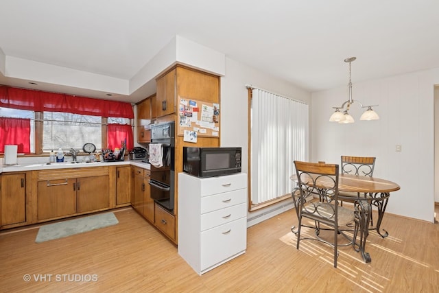 kitchen with black appliances, brown cabinets, light wood finished floors, and a sink