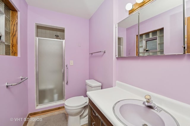 bathroom with baseboards, vanity, toilet, and a shower stall