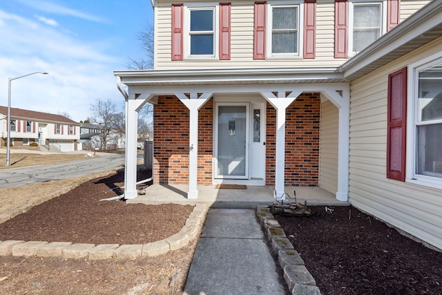 doorway to property featuring brick siding and a porch