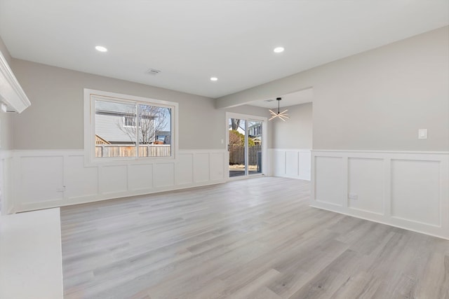 empty room featuring recessed lighting, light wood-style flooring, visible vents, and a wainscoted wall