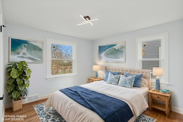 bedroom featuring visible vents, baseboards, and wood finished floors