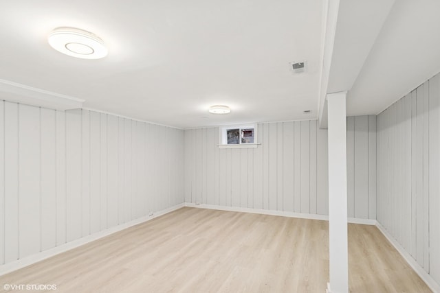 basement featuring light wood-type flooring, baseboards, and visible vents