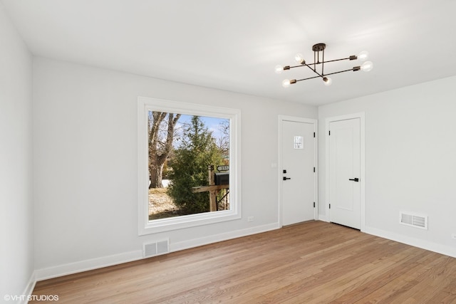 entryway with visible vents, baseboards, light wood-type flooring, and an inviting chandelier