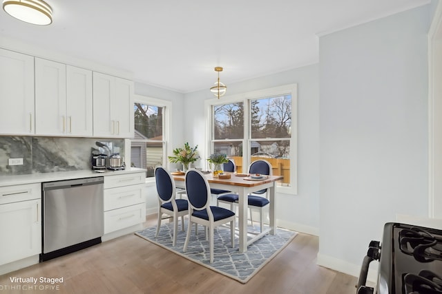 dining area with light wood-type flooring, baseboards, and crown molding