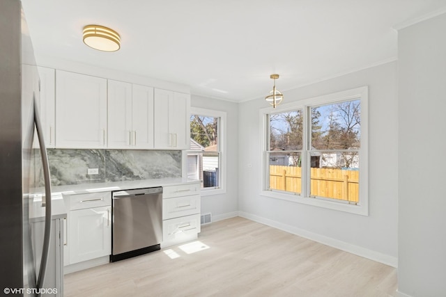 kitchen with backsplash, appliances with stainless steel finishes, white cabinets, and light countertops