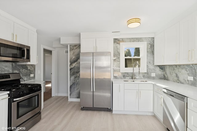 kitchen featuring a sink, white cabinetry, appliances with stainless steel finishes, light countertops, and decorative backsplash