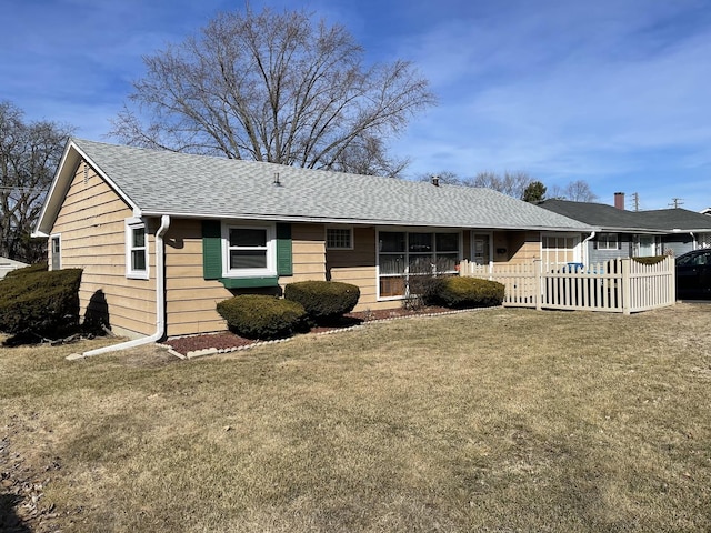 view of front facade featuring a front lawn, fence, and a shingled roof