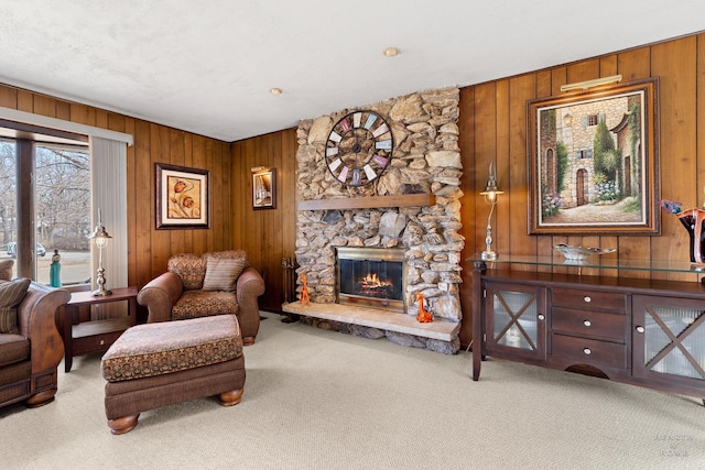 carpeted living room with a stone fireplace and wood walls